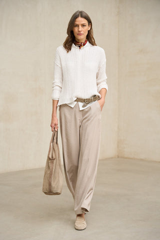 Look en tonos neutros con jersey de punto perlado y pantalón beige con accesorios a juego