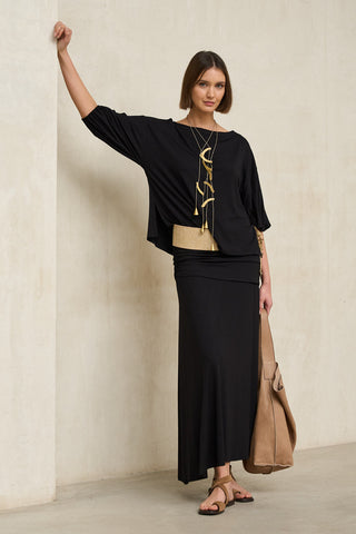 look total black de mujer con falda larga y camiseta fluida, combinado con fajín color arena y bolso marrón